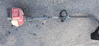 Full view of trimmer showing curved shaft, engine, handle, guard