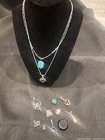 Overall lot showing two necklaces on display bust and loose pendants below