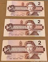 Three Canadian $2 banknotes aligned horizontally, obverse side up