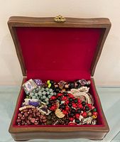 Open wood jewelry box showing full contents of costume jewelry