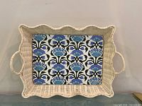 Full view of wicker tray showing scalloped rim and floral base