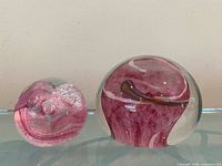 Two glass paperweights side by side showing relative sizes and swirl patterns