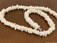 Coiled white puka shell chip necklace showing clasp
