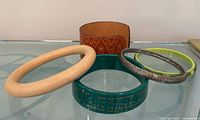 Five bracelets displayed on glass surface