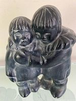 Front view of dark ceramic Inuit children sculpture