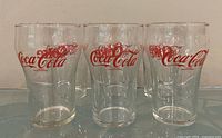 Front view of six Coca-Cola glasses showing logos and clear glass