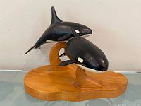 Front view of double-orca wooden sculpture on base