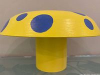 side view showing yellow top with blue polka dots and cylindrical base