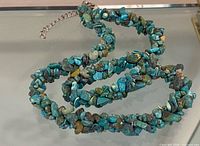 Full view of turquoise chip necklace coiled on surface