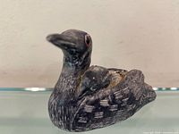 Left side profile of carved duck figurine showing glass eye and feather detail