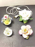 All four porcelain items grouped: rose night light with cord, three small floral figurines