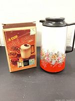 Percolator box beside floral thermos