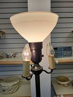 close view of lit frosted glass shade and two candelabra sockets