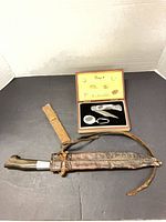 Overall lot showing fixed blade knife in sheath, leather strap, and boxed knife set