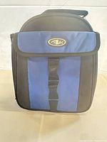 Front view showing blue panel, logo patch, buckle strap and zipper