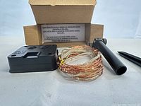 Coiled copper wire string lights, solar control box, mounting arm and cardboard box