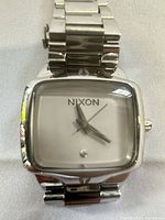 Front view of Nixon square silver watch face and bracelet