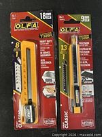 Front view of both OLFA SL-1 18 mm and PA-2 9 mm utility knives in sealed retail packaging