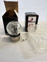 Light removed from box showing crackle glass globe, silver top with clip, original box, bubble wrap