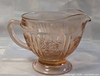 Angled view showing handle, rose pattern and pedestal base