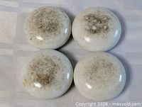 Four white porcelain door knobs grouped together