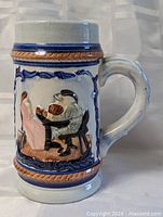 Full view of ceramic beer stein mug showing handle and relief scene