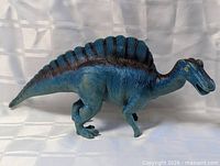 Full left-side view of blue dinosaur toy showing sail and stance