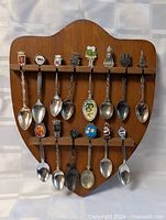 Full view of wooden shield rack holding 17 collector spoons