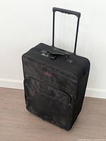 Front view of black Globe Trotter wheeled suitcase showing telescopic handle and front pocket
