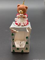 Front view of teddy bear ornament on torn box