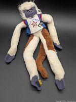 Full view of plush lanky monkey showing overall design, jersey and tag