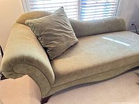 Full view chaise lounge with pillow, showing rolled arm and wood legs