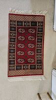 Full view of red Bokhara style accent rug showing pattern and fringe