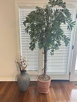 Artificial olive tree beside vase for scale