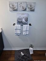 Front view showing towel holder, bath mat, two hand towels on wall bar, and four canvas prints