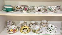 Full shelf view showing both rows of teacup and saucer sets