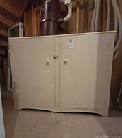 Front view of off-white wooden cabinet with two doors and knob pulls