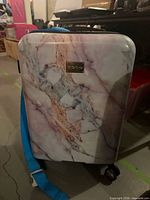 Front view of pink marble bebe hardside suitcase with logo plaque and wheels visible