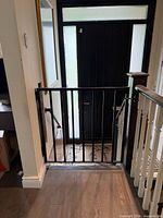 Gate installed across stair opening, front view showing latch side and hinges