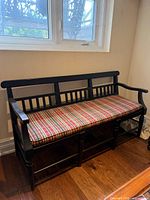 Full view of black painted three-seat bench under window