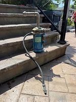 Full view of Goulds pump motor with attached hose and fittings on stone steps