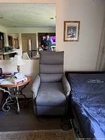 Front view of gray power lift chair next to bed