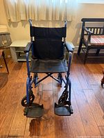 Front view of Hugo blue transport wheelchair showing seat, footrests and armrests