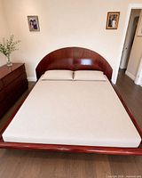 King platform bed with mattress showing arched headboard and wood finish