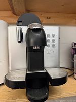 Front view of Nespresso DeLonghi capsule coffee machine showing brewing head, drip trays and control panel