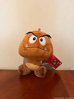 Front view of Goomba plush showing face, tag, and overall condition