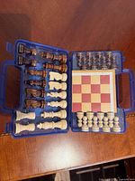 Open case showing 32 chess pieces, folded board, storage layout