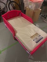 Full view of pink toddler bed with mattress