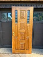 Full front view of carved wood door with leaded glass and hardware