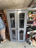 Front view of gray metal cabinet with glass panels and lock hardware